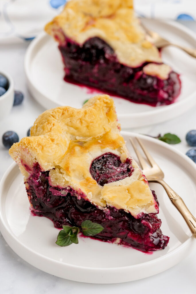 two slices of blueberry pie. This pie has a homemade filling and flaky homemade crust