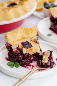 A slice of blueberry pie, with a bite taken out, flaky crust, thick filling