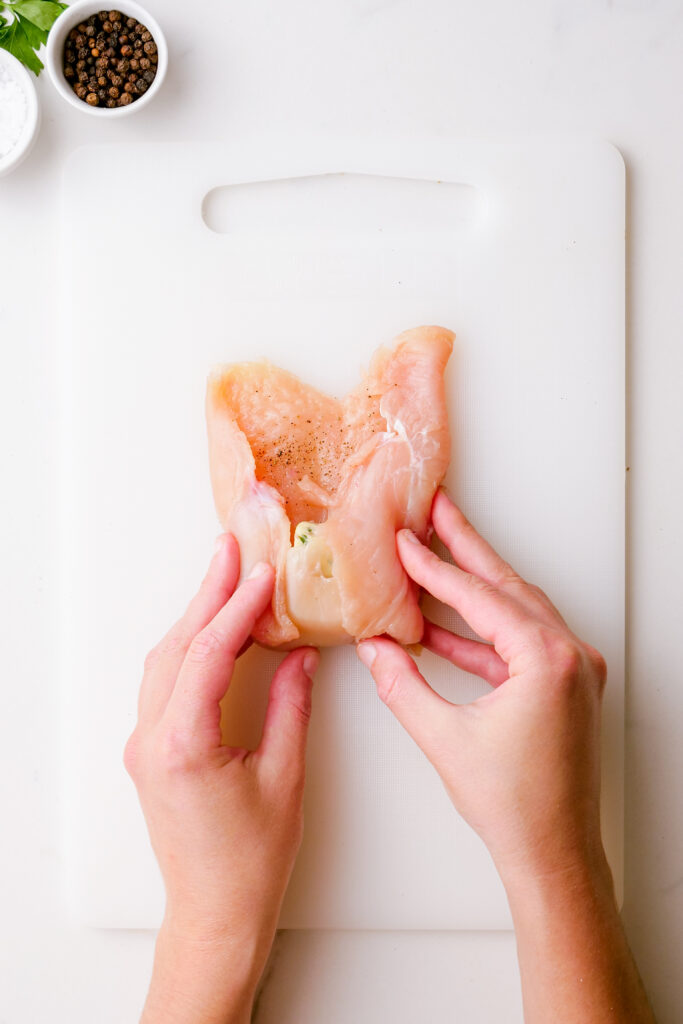 Rolling chicken into a packet with herbed butter in the center.