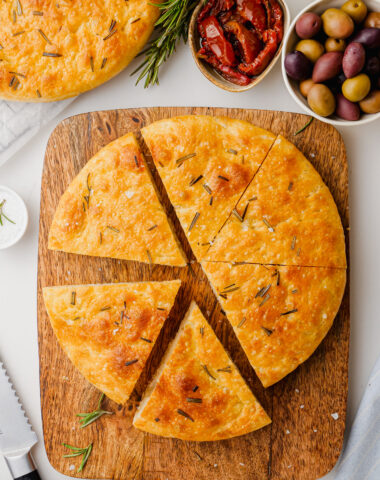 A loaf of homemade focaccia on a wooden cutting board.