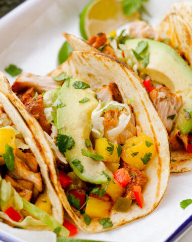 Making grilled fish tacos, assembled into tacos on a white plate