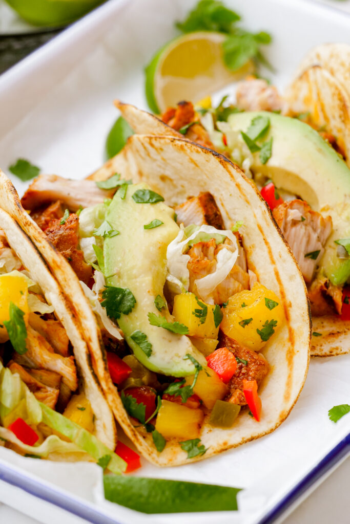 Making grilled fish tacos, assembled into tacos on a white plate