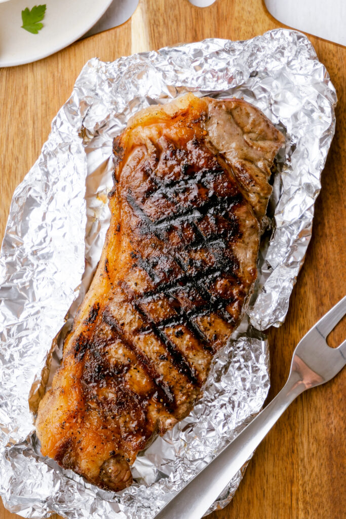 A seasoned and cooked strip steak for serving with chimichurri