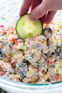 Loaded ranch dip with cucumbers being dipped into it.