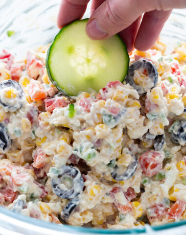 Loaded ranch dip with cucumbers being dipped into it.