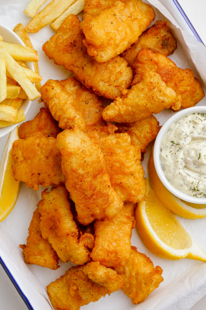 Crispy Beer Battered Fish Recipe, a bunch of fish on a platter with fries and tartar sauce