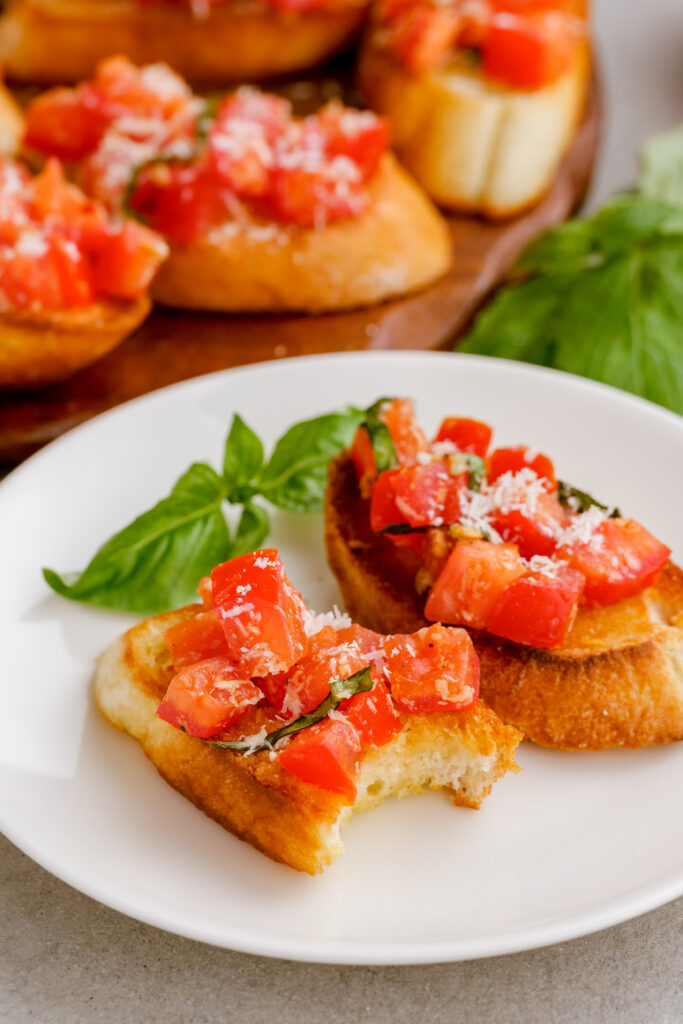 A plate of bruschetta on toasted bread, with a bite taken out