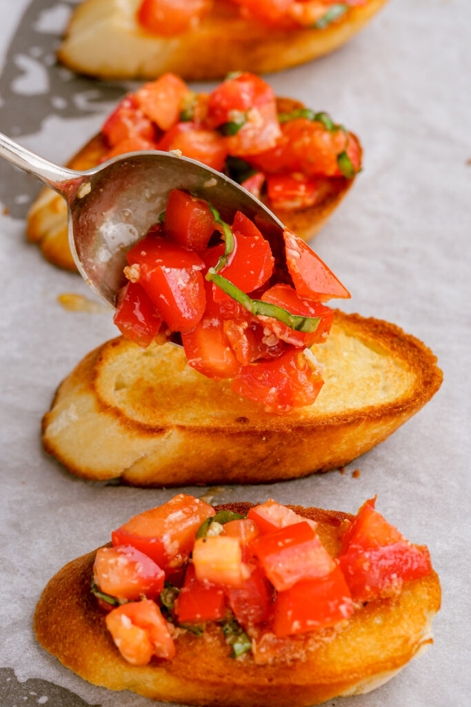 Assembling bruschetta on top of toasted baguettes
