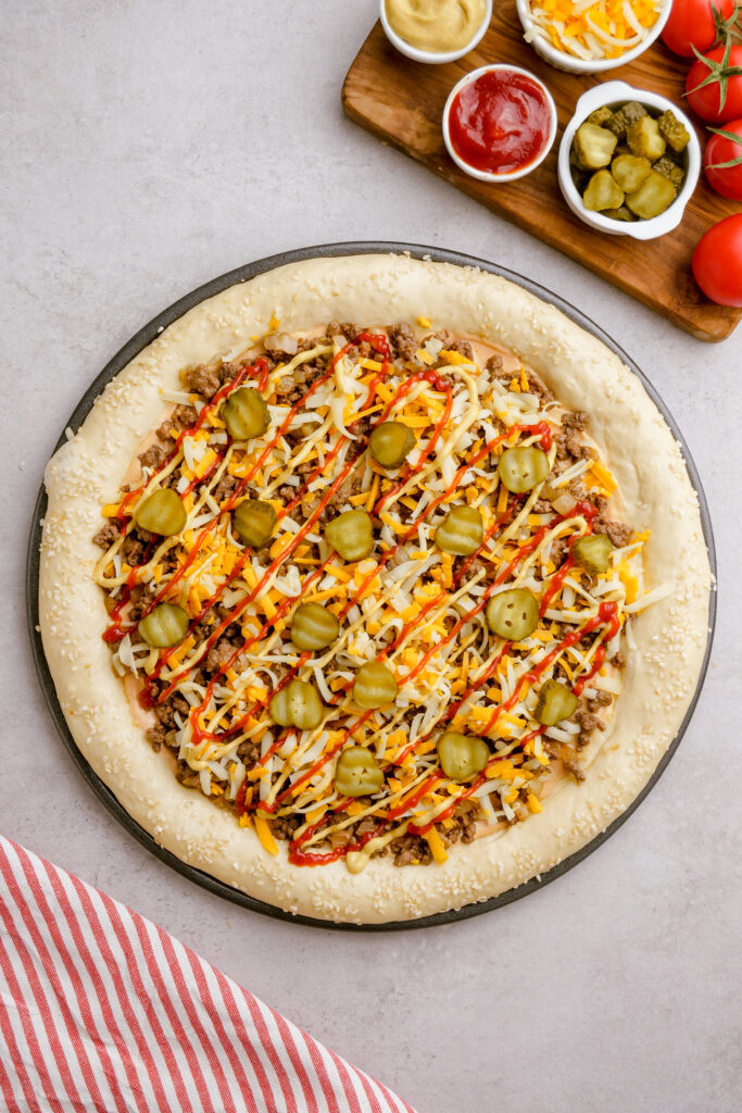 An unbaked but topped cheeseburger pizza