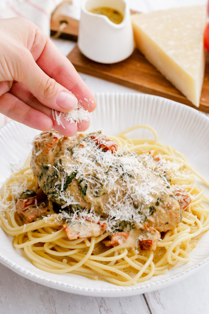 Garnishing tuscan chicken with parmesan cheese