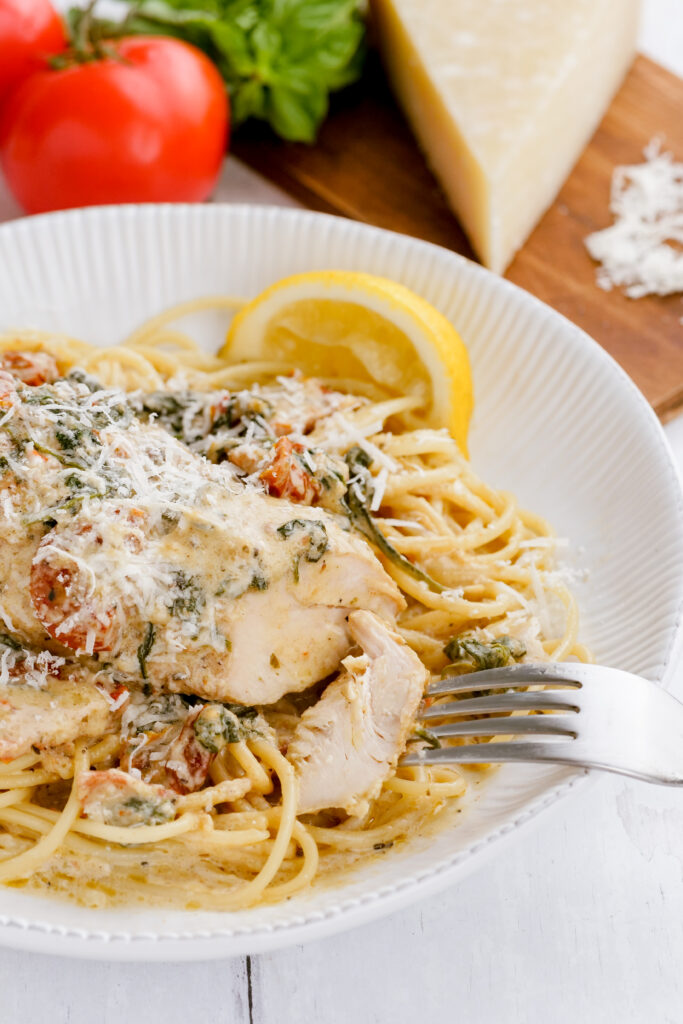 A plate of instant pot pressure cooker tuscan chicken on a bed of pasta