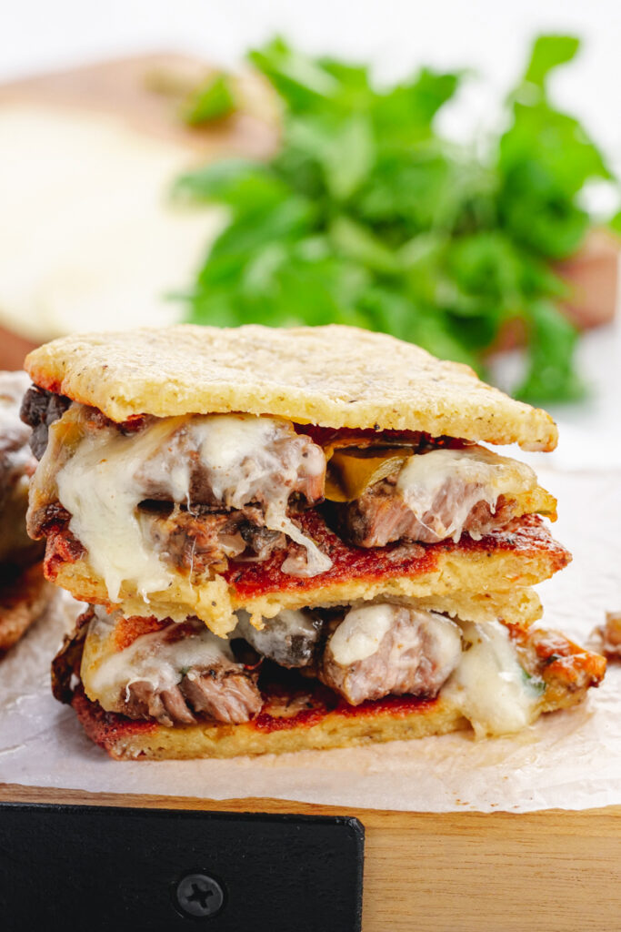 Keto philly cheesesteaks made in the crock pot on a cheese bread bun