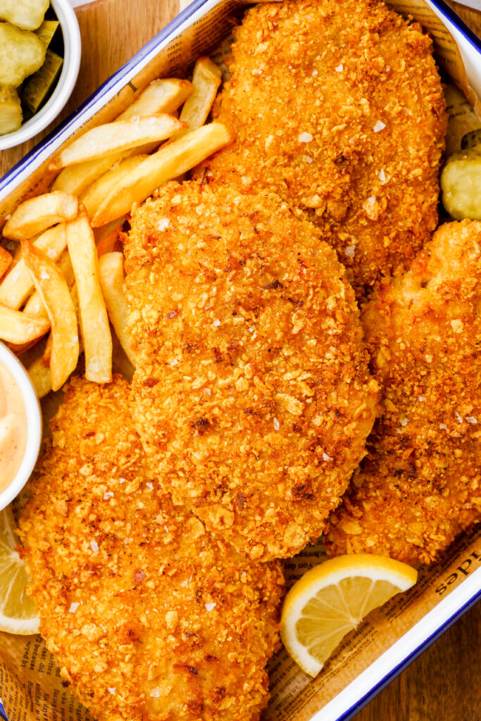 Oven fried chicken and french fries on a tray with lemons for garnish