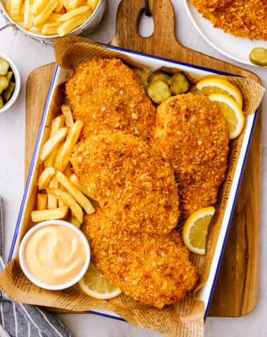 Oven fried chicken on a baking tray with sauce and fries