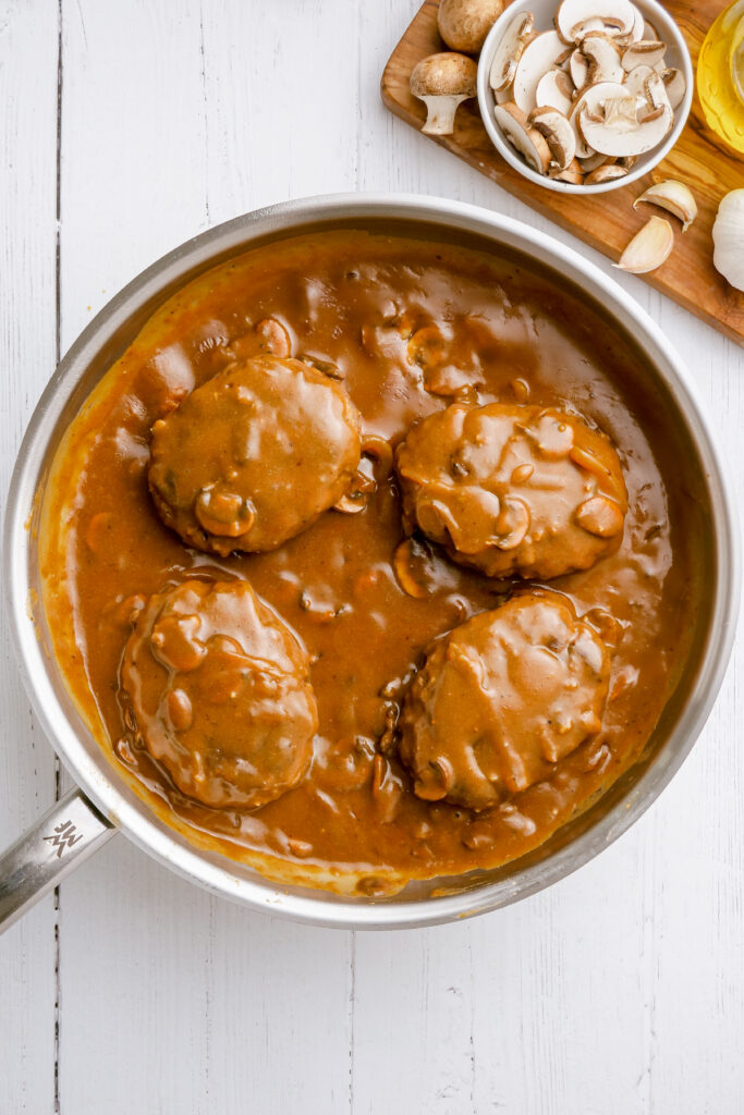 A skillet with salisbury steak in it and mushroom gravy