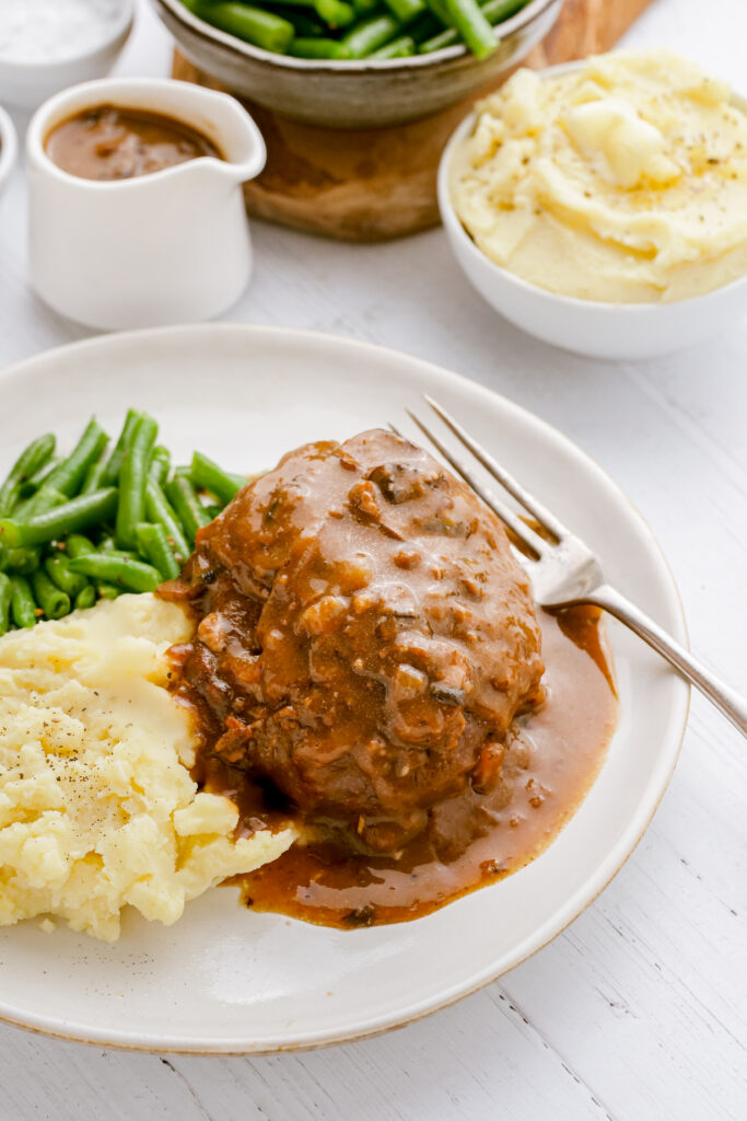 A plate with salisbury steak patty and sides