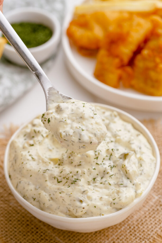 Homemade tartar sauce in a bowl being spooned out to go with fish and chips