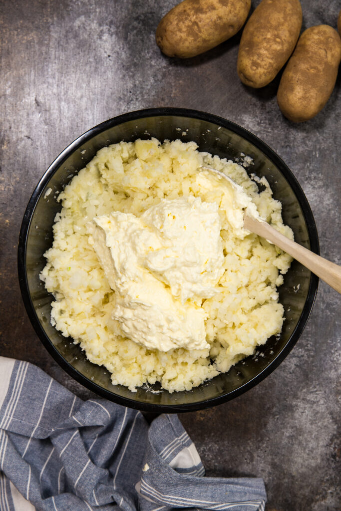 Mixing together your potatoes and the mixture of cream cheese, egg, etc. that make them so flavorful. 