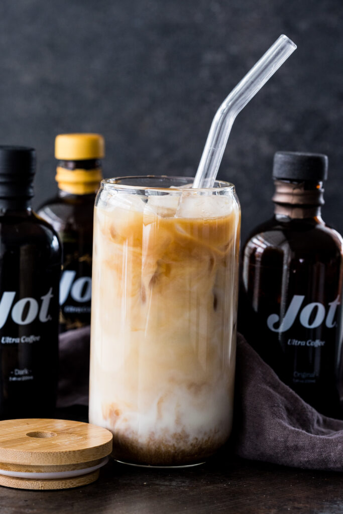 Iced Vanilla Oat Latte made with Jot Coffee and served in a tall glass with a reusable straw