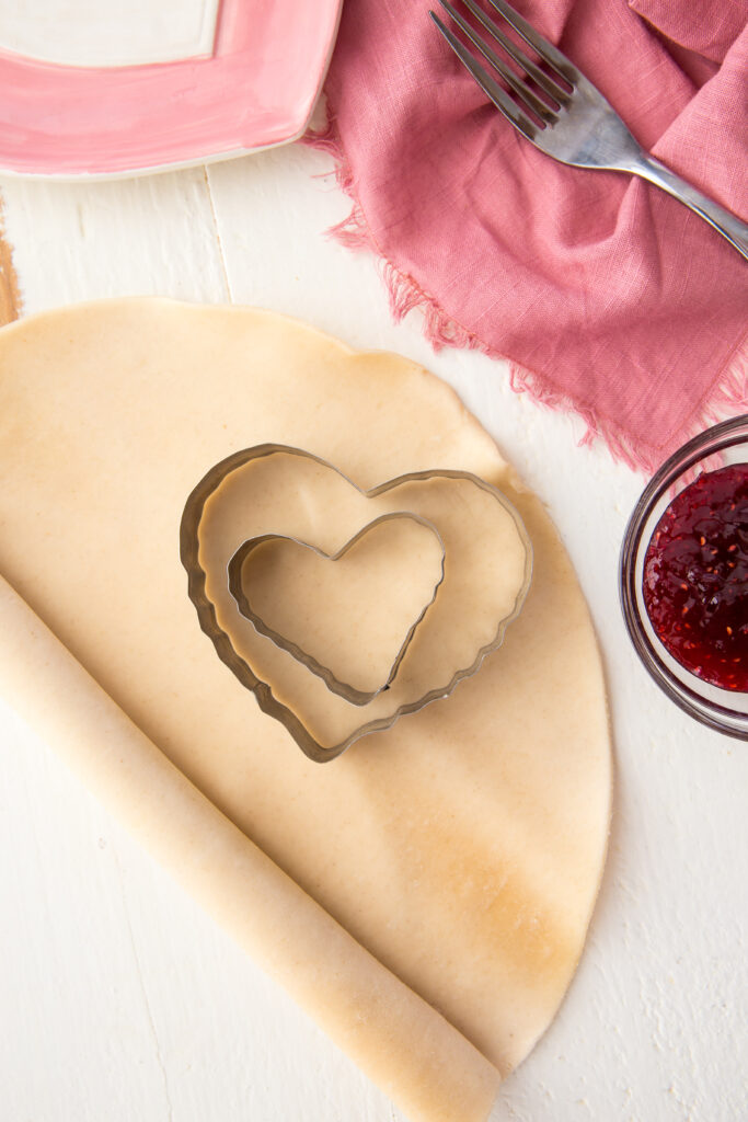 Cutting out the hearts for homemade pop tart hearts. Buttery, flakey, raspberry homemade pop tarts.