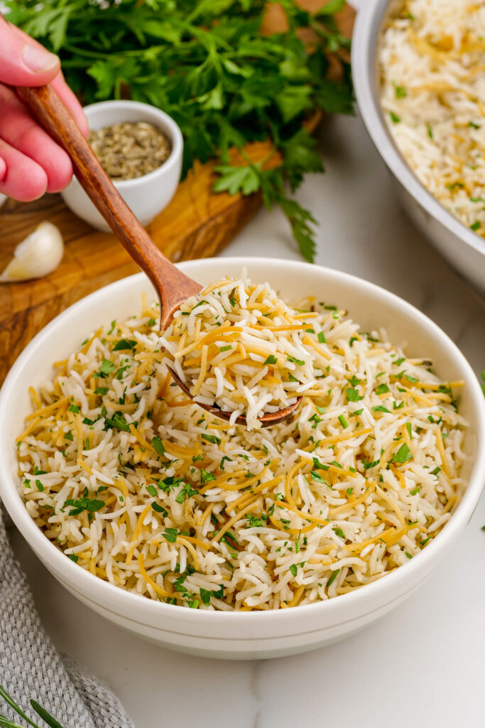 A white bowl filled with herbed rice pilaf. Herbed rice pilaf, this easy side dish is loaded with flavor, fresh herbs, and more. 