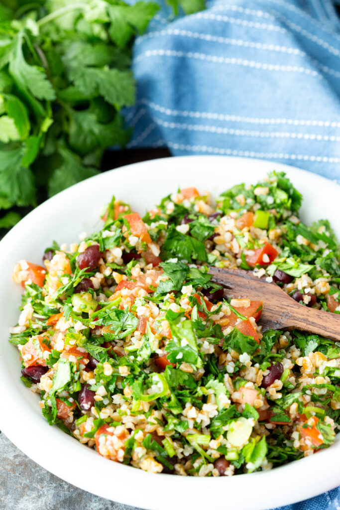 A plate of tabbouleh, a fresh herb salad with pomegranate arils, tomatoes, and bulgur.