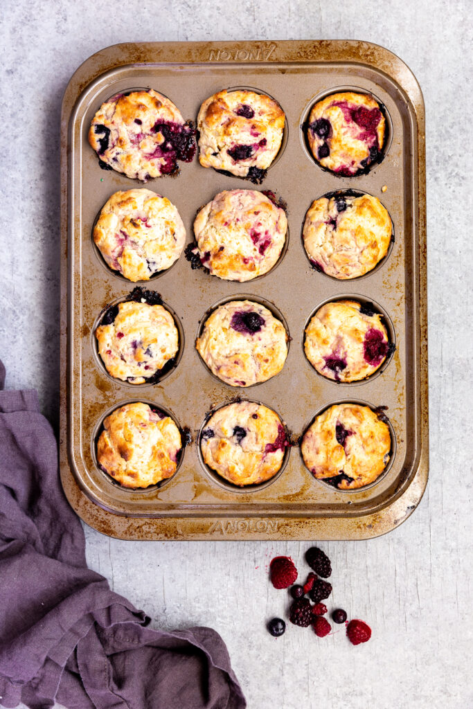 A tray of triple berry muffins, a tender muffin loaded with blackberries, blueberries, and raspberries