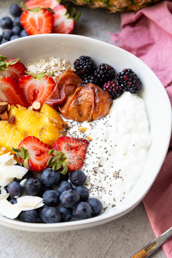 Grilled fruit, fresh berries, nuts, seeds, coconut, and cottage cheese make this high protein breakfast bowl a real treat. 