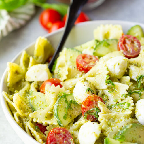 Pesto Pasta Salad with bowtie pasta, fresh tomatoes and cucumbers, and mozzarella cheese.