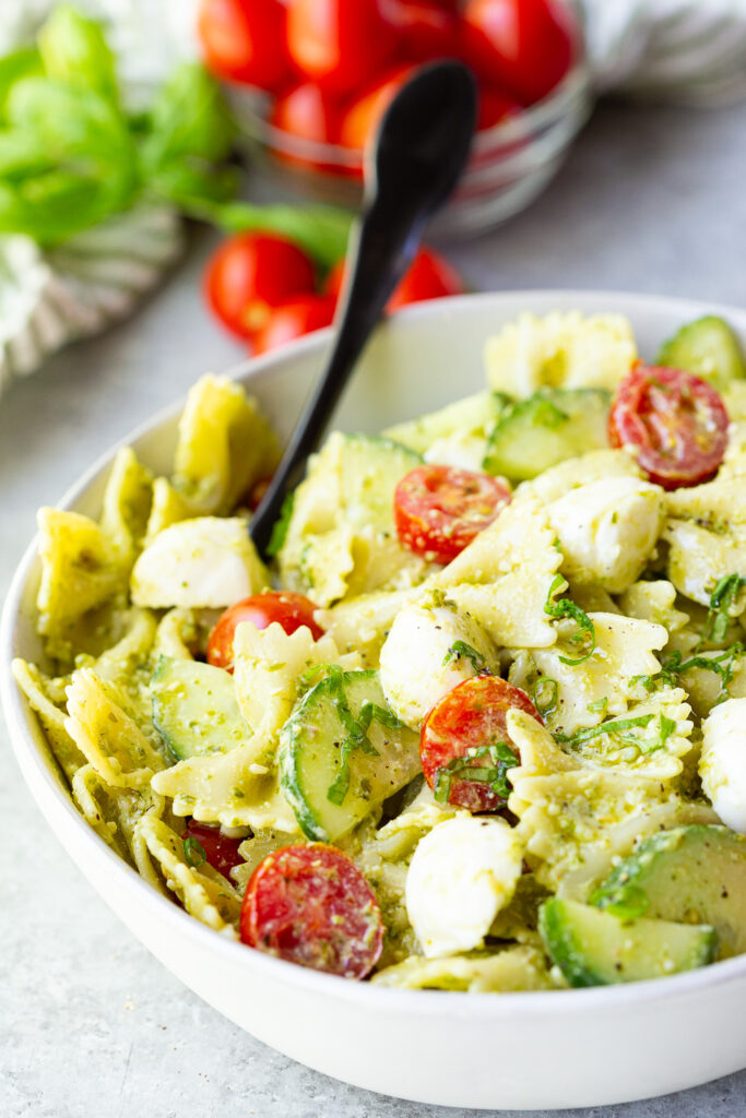 Pesto Pasta Salad with bowtie pasta, fresh tomatoes and cucumbers, and mozzarella cheese.