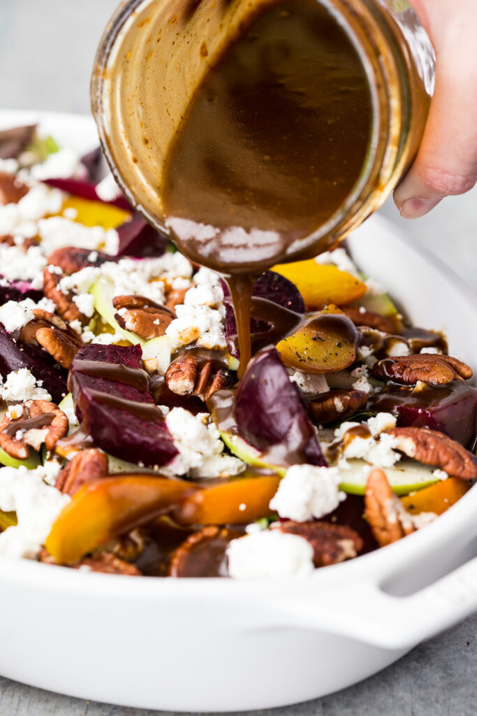 Pouring balsamic vinaigrette on a salad