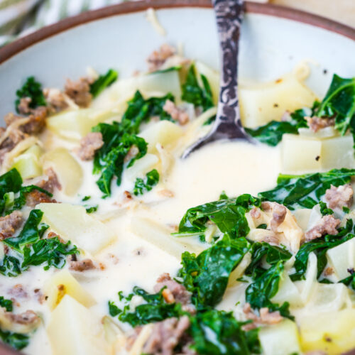 A warm bowl of zuppa toscana soup, a creamy broth with tender potatoes, spicy sausage, and hearty kale.