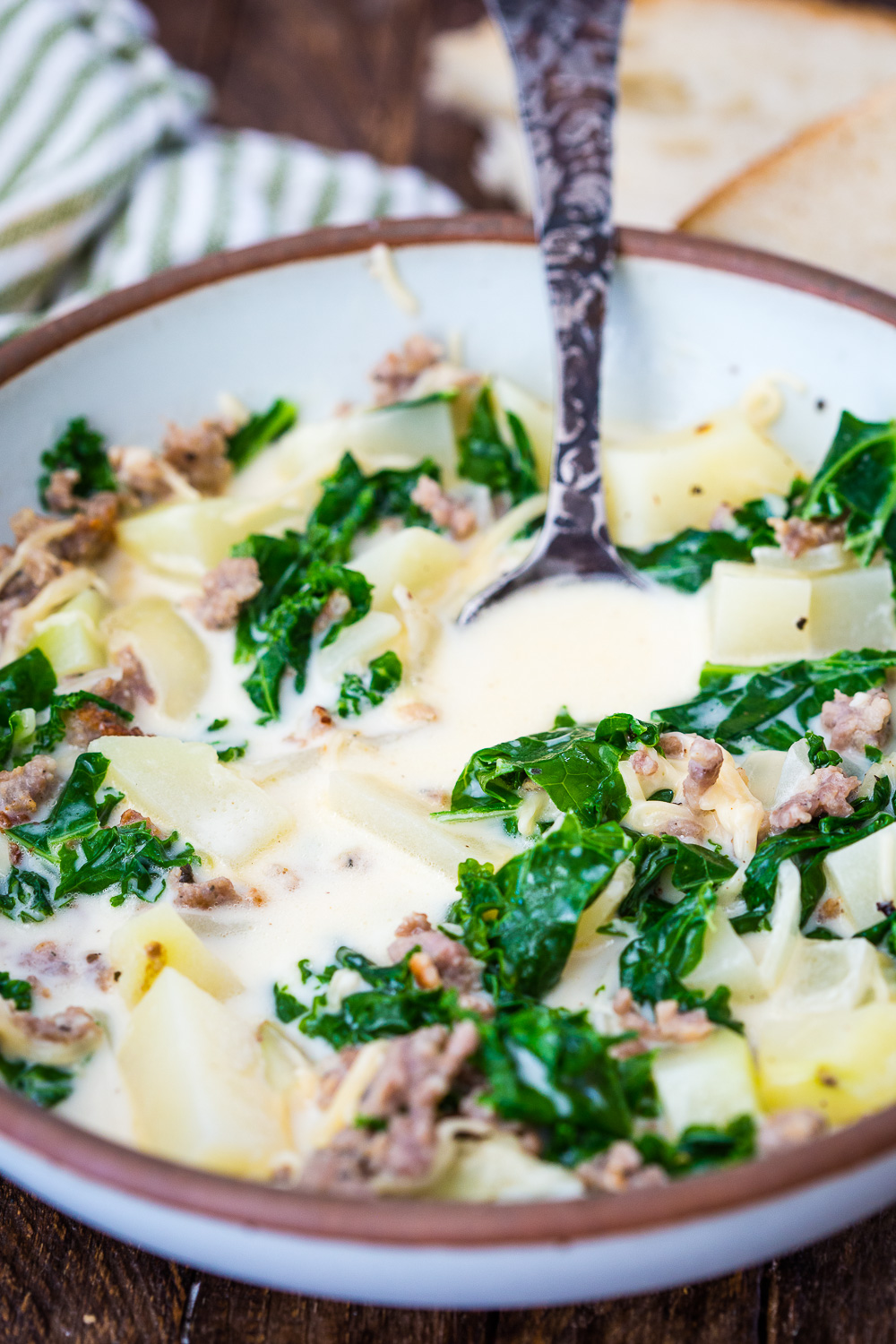 A warm bowl of zuppa toscana soup, a creamy broth with tender potatoes, spicy sausage, and hearty kale.