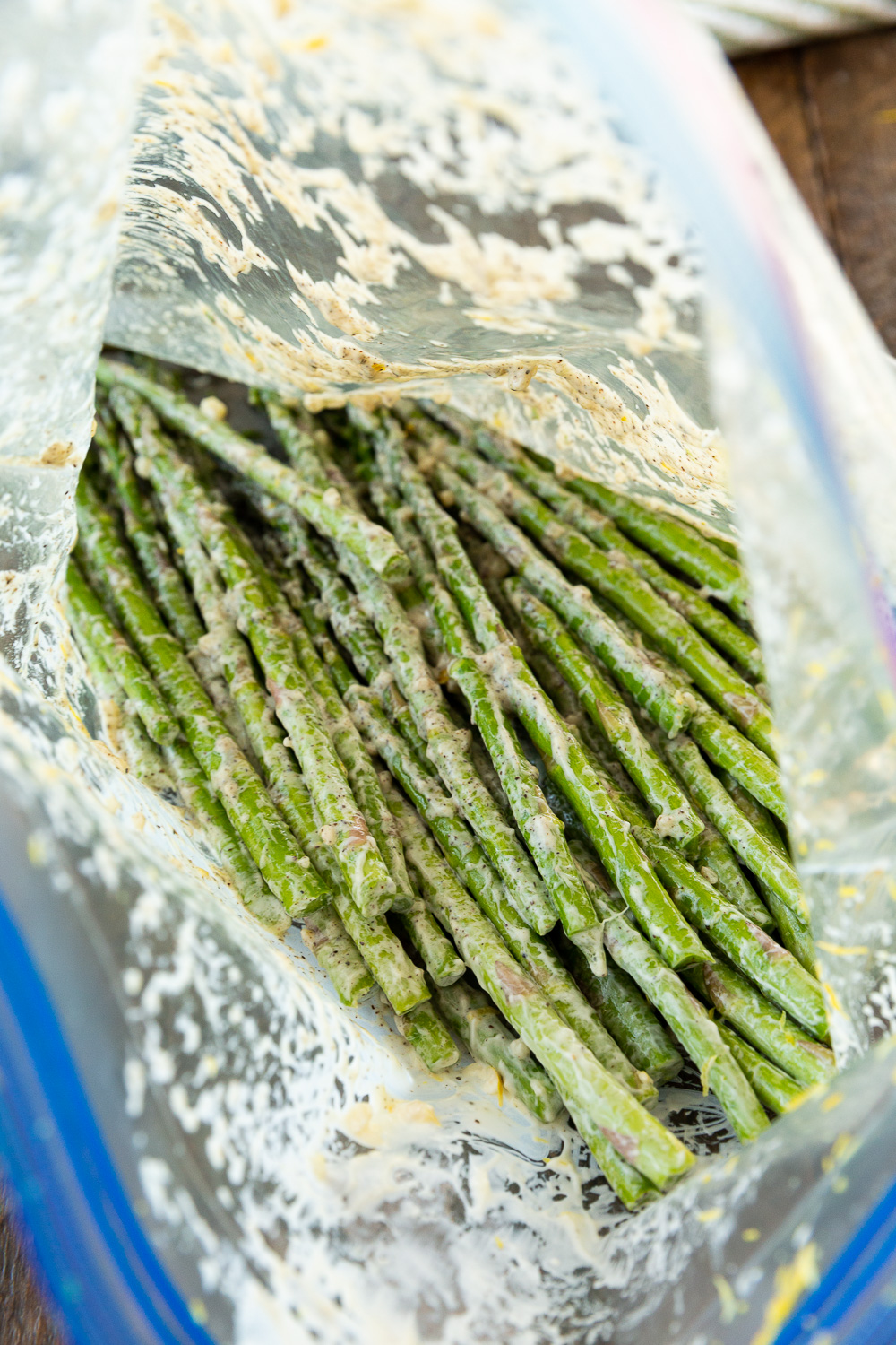 Shaking asparagus in a zip top bag with ingredients to coat it before putting it in the air fryer. 