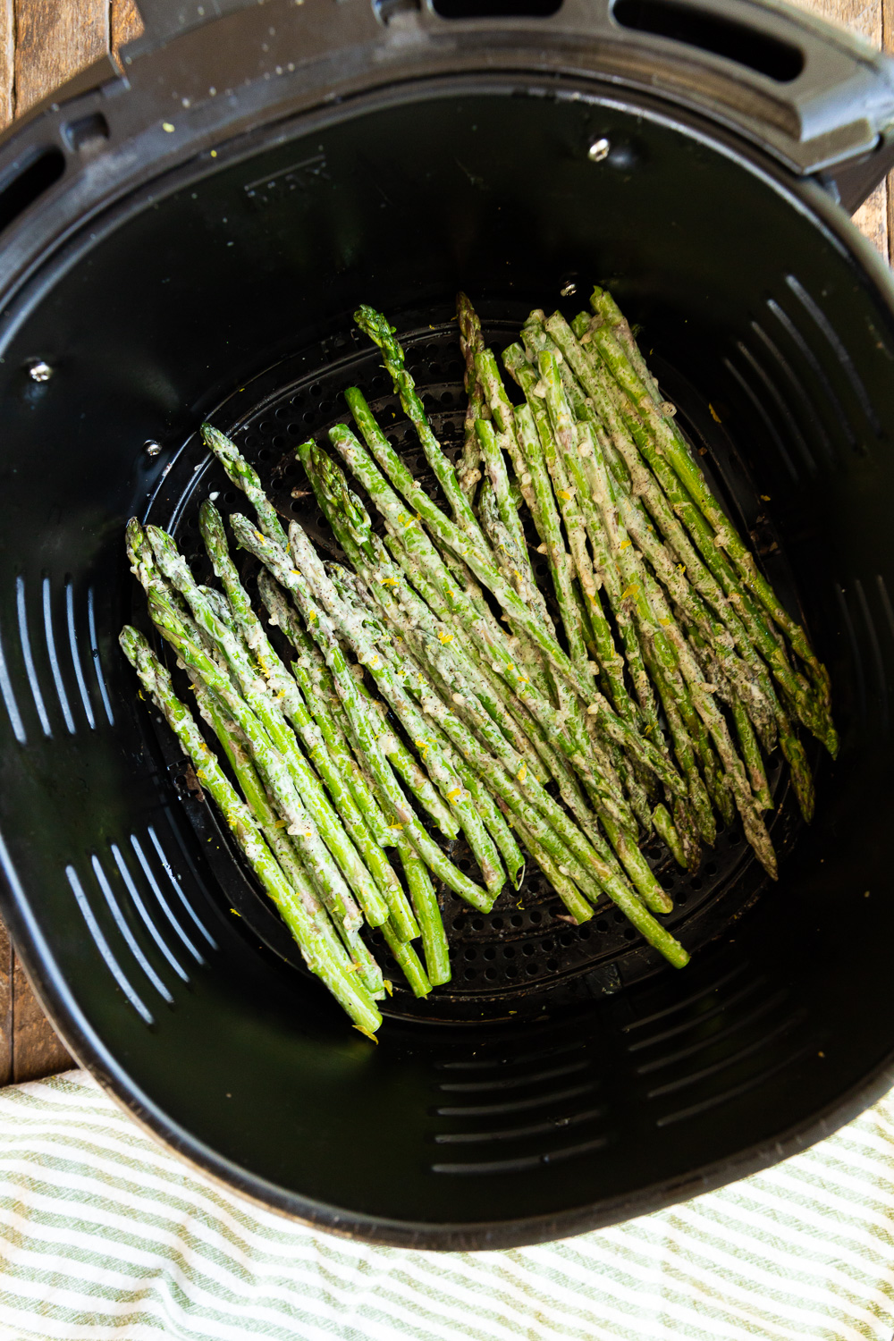 Asparagus in an air fryer basket to be cooked. 