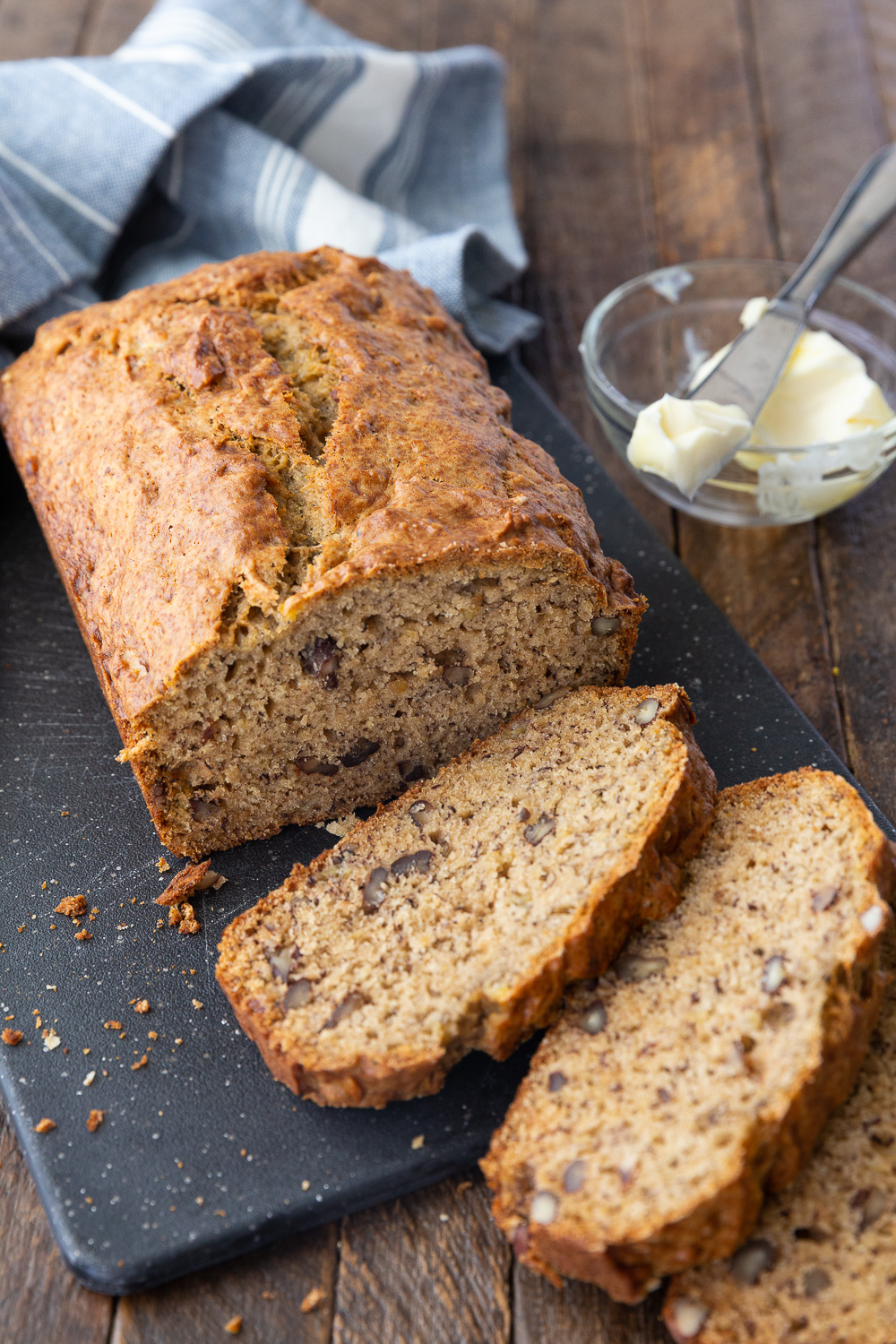 Browned butter banana bread with a few pieces cut and butter for serving it. 