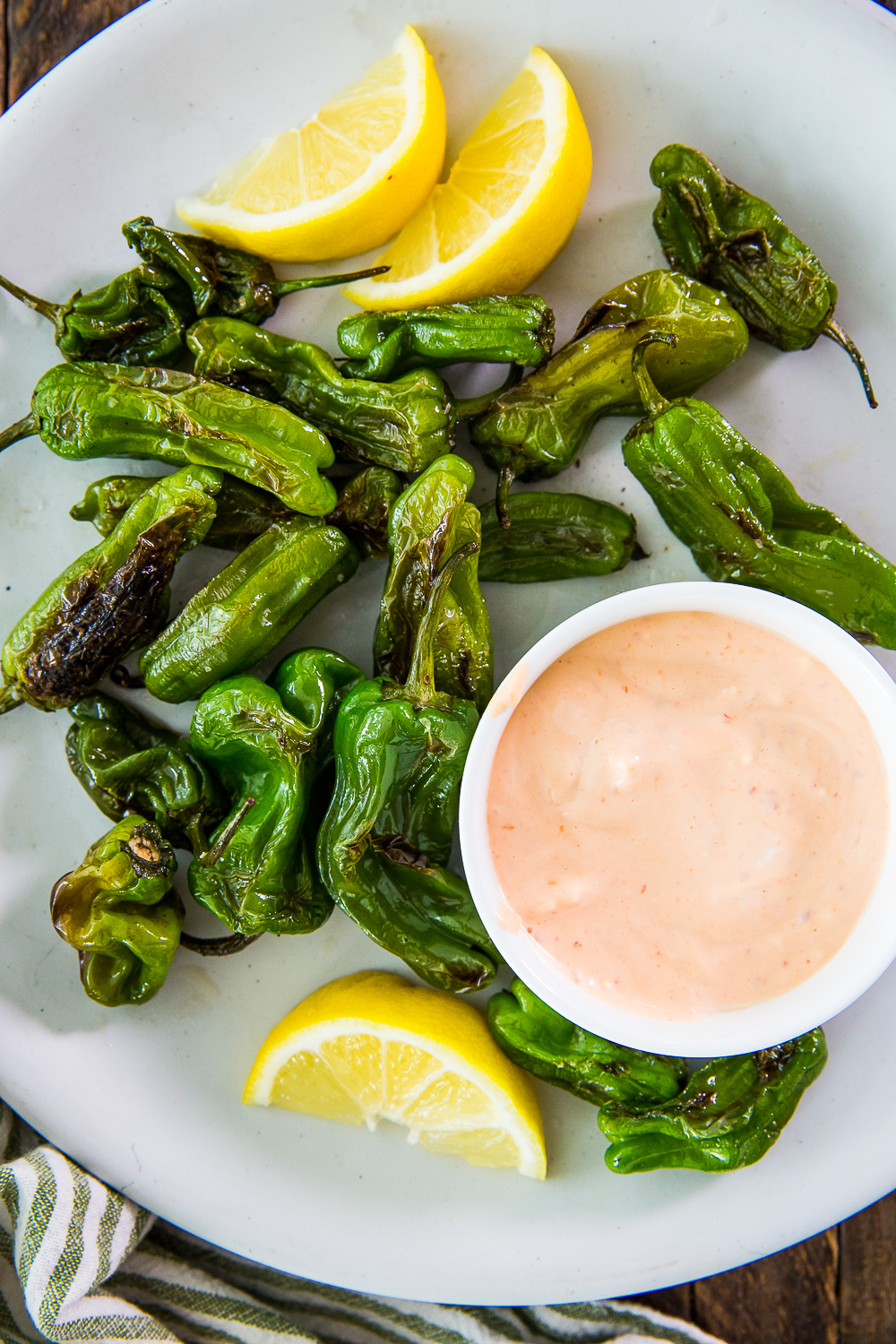 A plate of shishito peppers after being blistered in a cast iron skillet. 