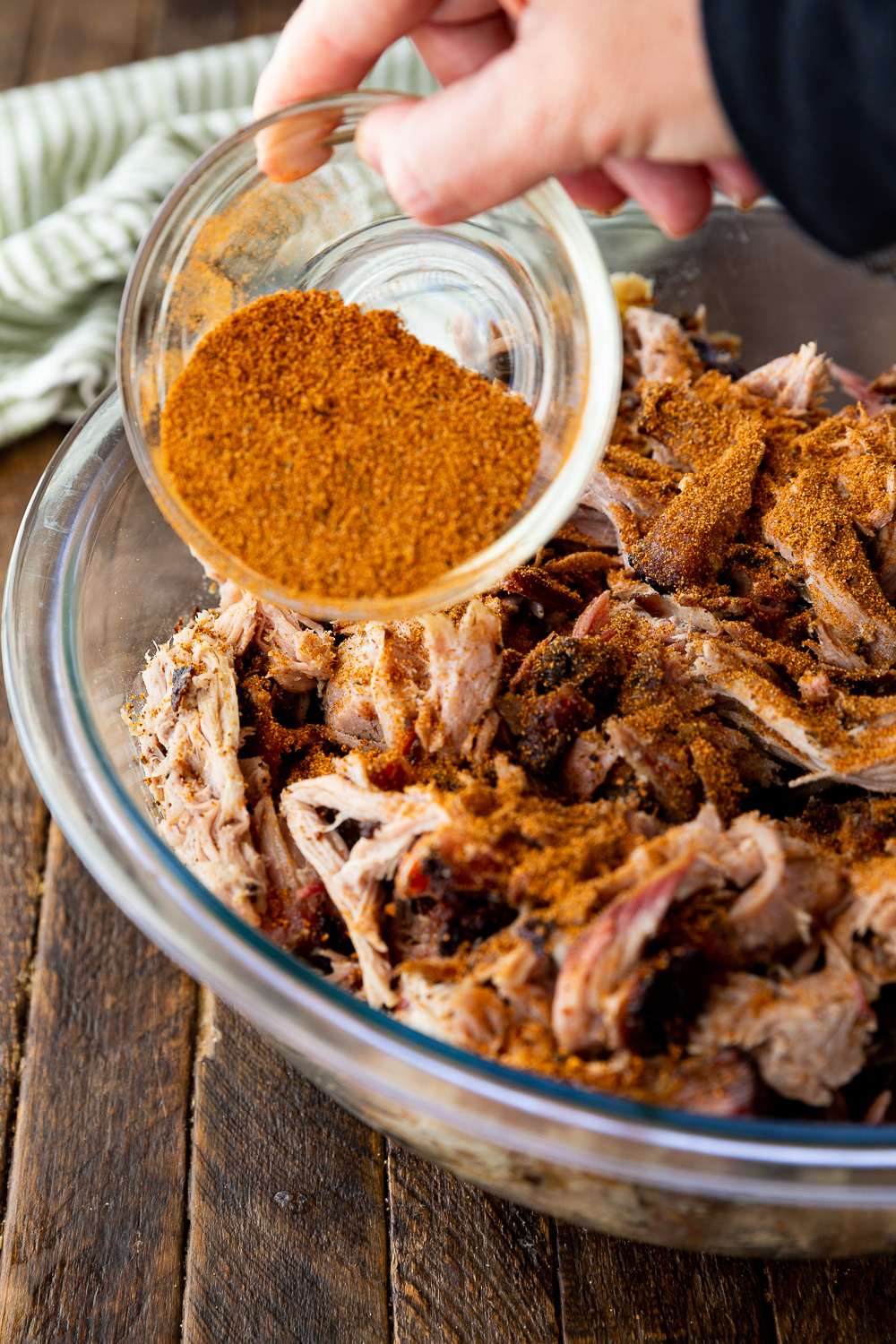 Adding seasoning to your cajun style pulled pork after cooking. 
