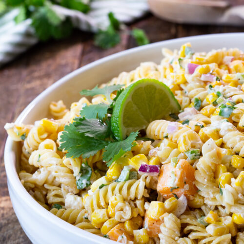 Mexican Street Corn Pasta Salad garnished with lime and cilantro. Creamy pasta salad reminiscent of elote.