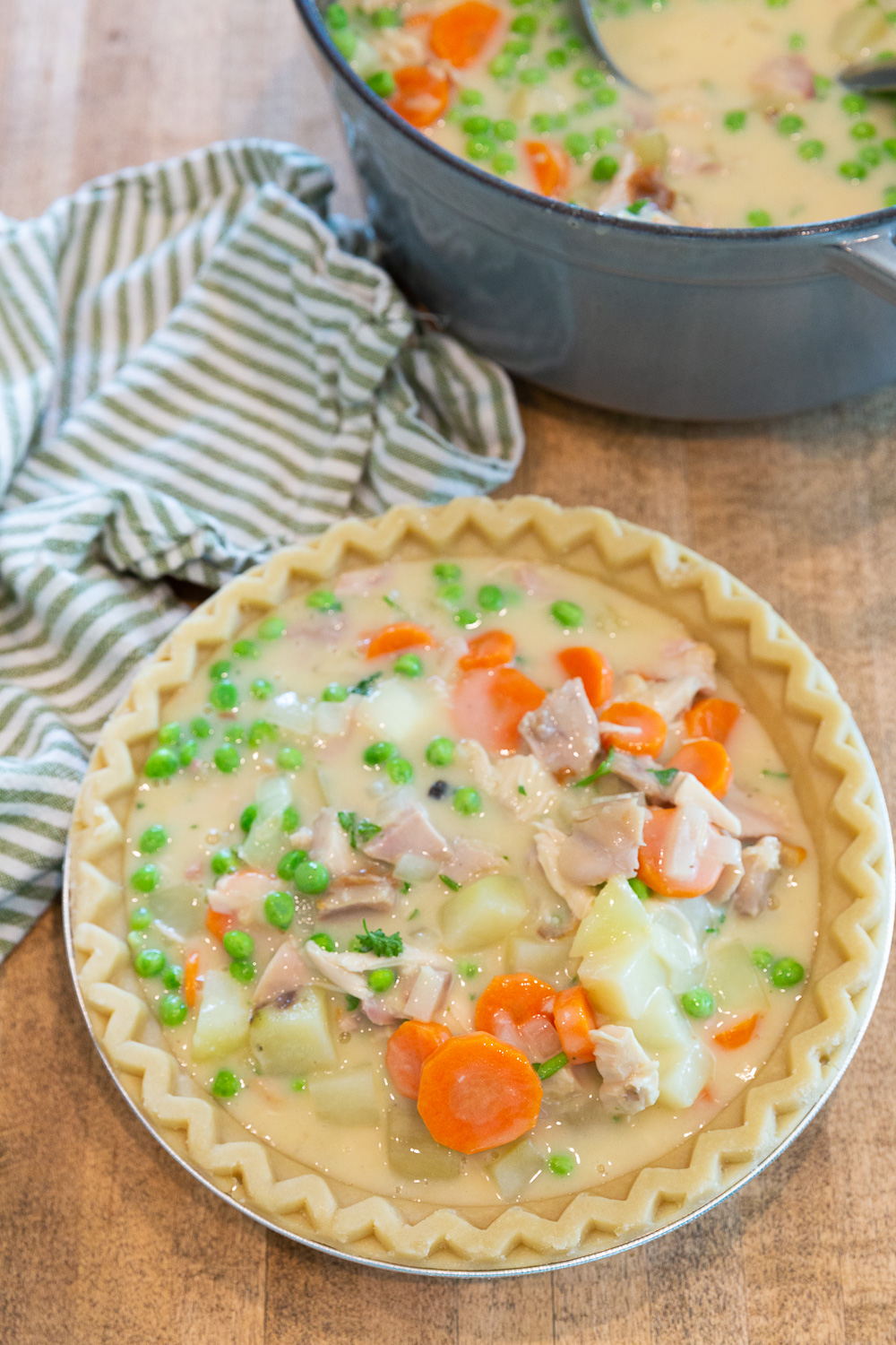 Pouring filling into the pie crust for chicken pot pie. 