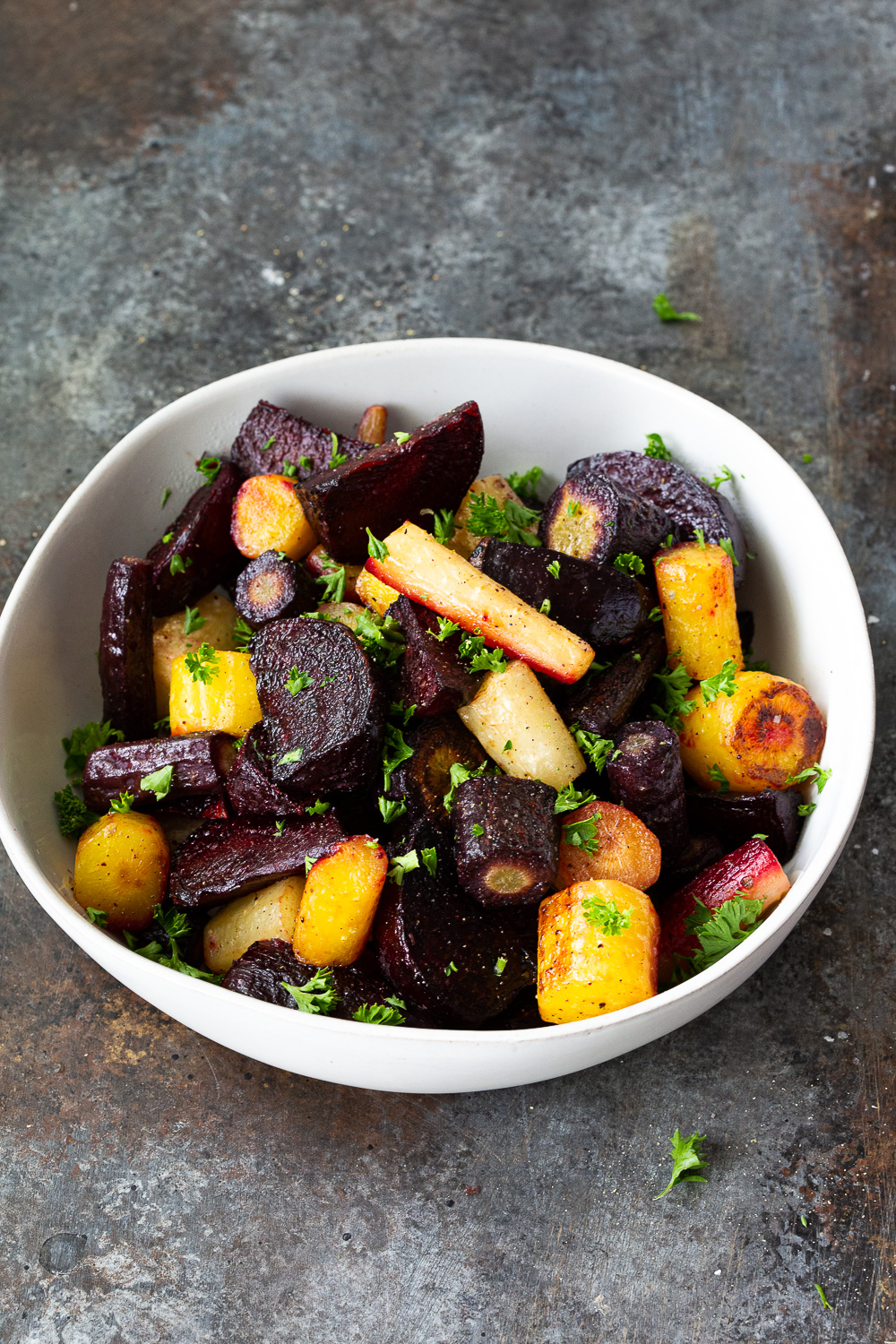 A bowl of roasted beets and carrots garnished with fresh parsley. 