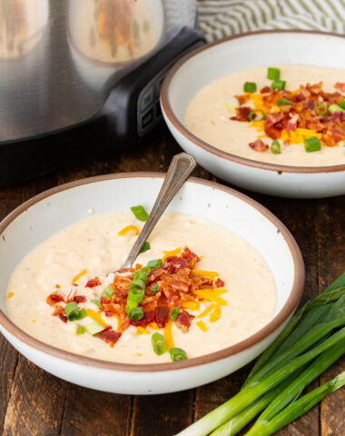 Crock pot loaded baked potato soup topped with crispy bacon, chives, and cheese