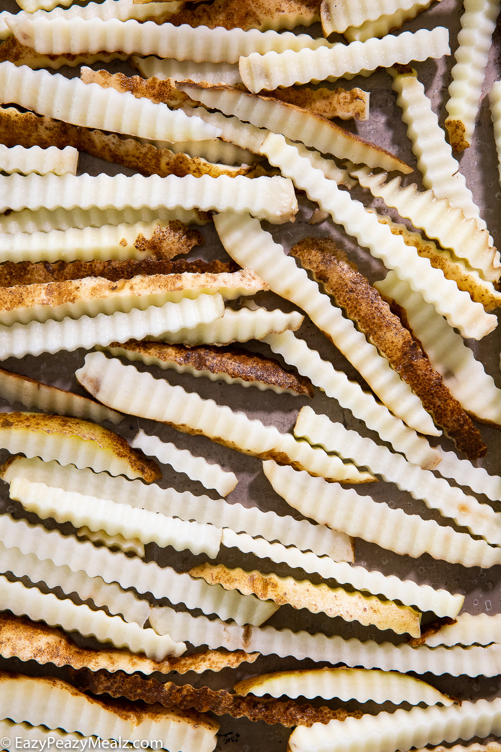 A tray of crinkle cut fries, seasoned and ready to bake. 