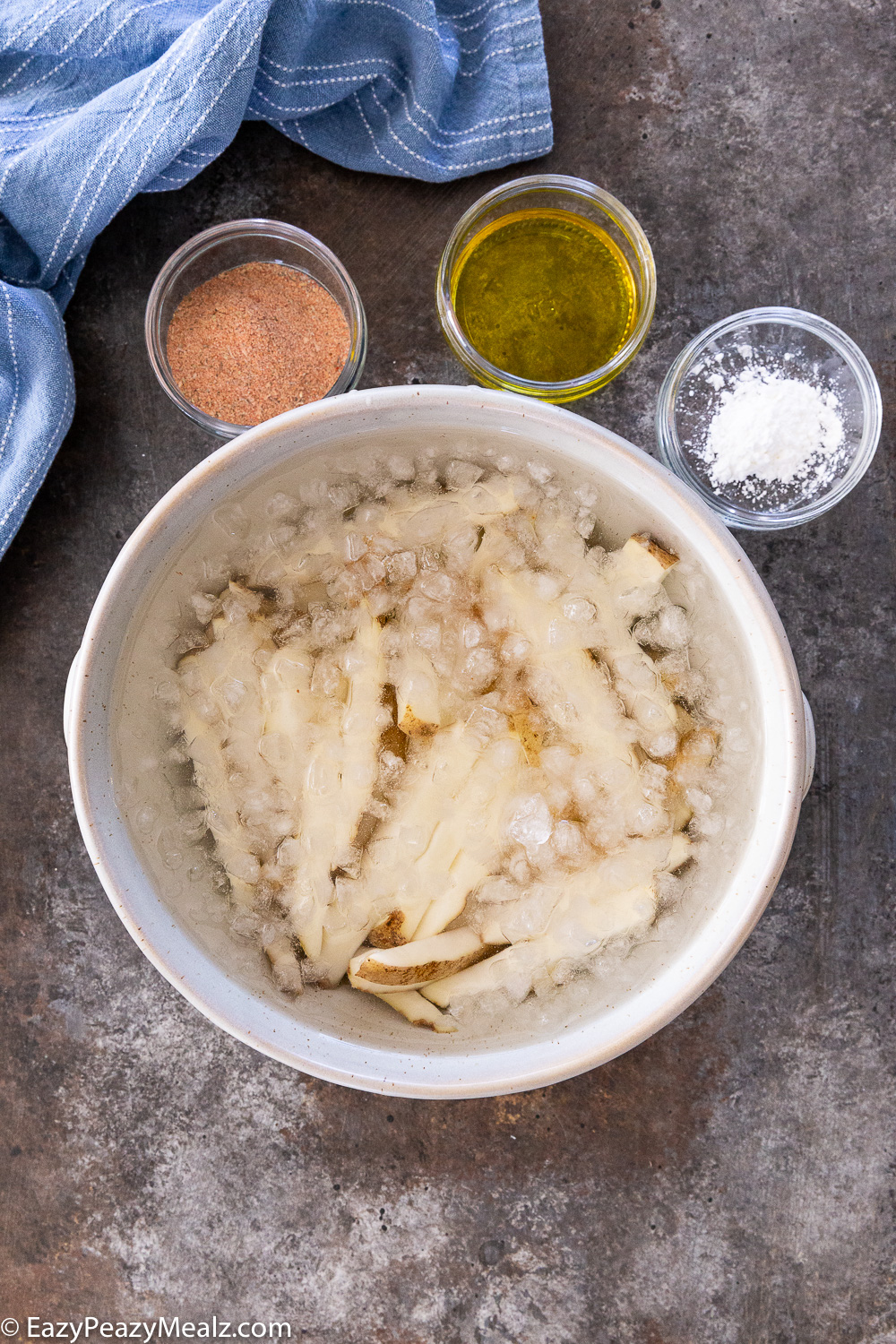 Cajun fries being soaked in ice water to result in crispy fries. 