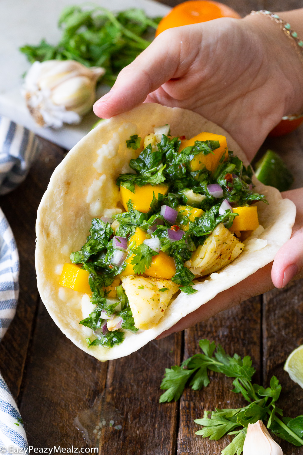 Assembling halibut fish tacos, with a grilled citrus marinated halibut and a mango and chimichurri topping
