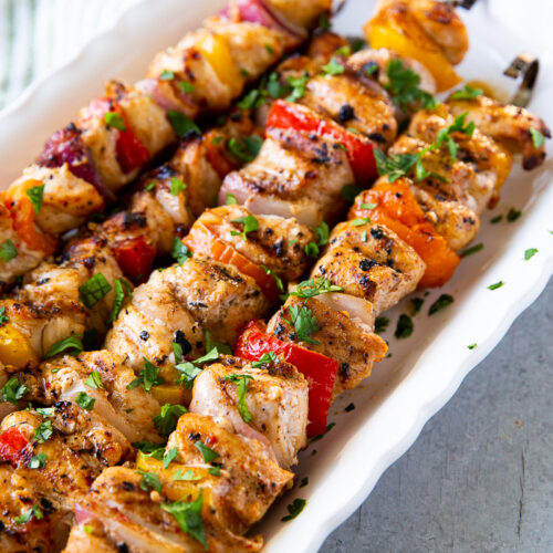 Grilled chicken skewers with charred bell peppers and onions, served hot off the grill with a golden, caramelized finish.