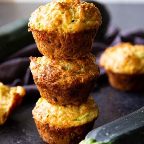 Zucchini muffins stacked and ready to serve—these savory bites are perfect for lunchboxes, brunch, or an on-the-go snack.