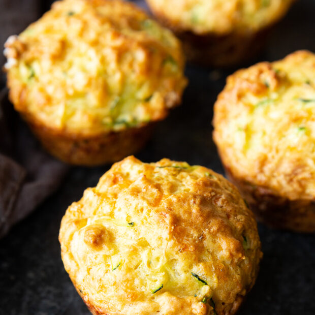 Golden, cheesy zucchini muffins fresh from the oven, with a perfectly crisp top and soft, savory center—ideal for breakfast or snacking.