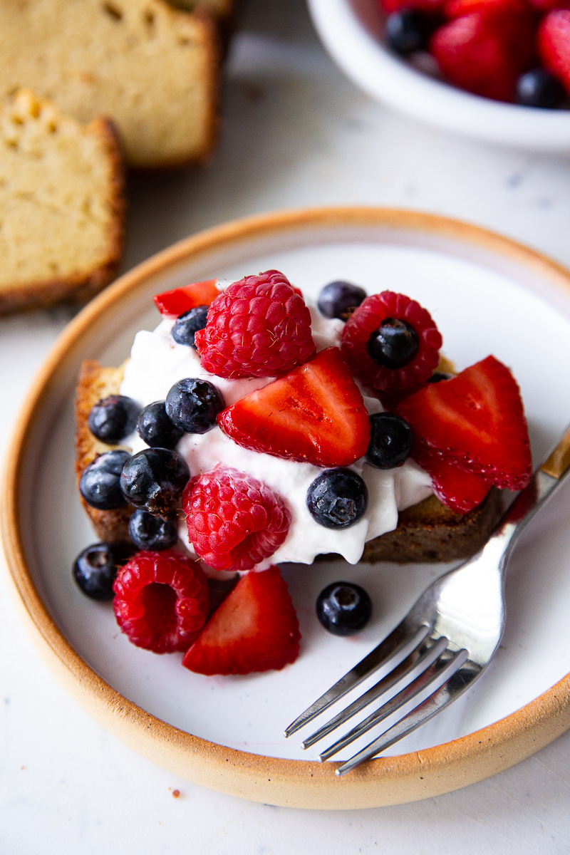 A thick slice of golden pound cake topped with fluffy whipped cream and a vibrant mix of fresh berries—rich, moist, and bursting with flavor.