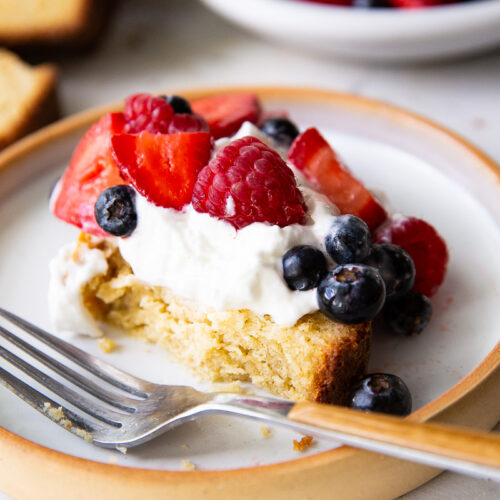 A thick slice of golden pound cake topped with fluffy whipped cream and a vibrant mix of fresh berries—rich, moist, and bursting with flavor.